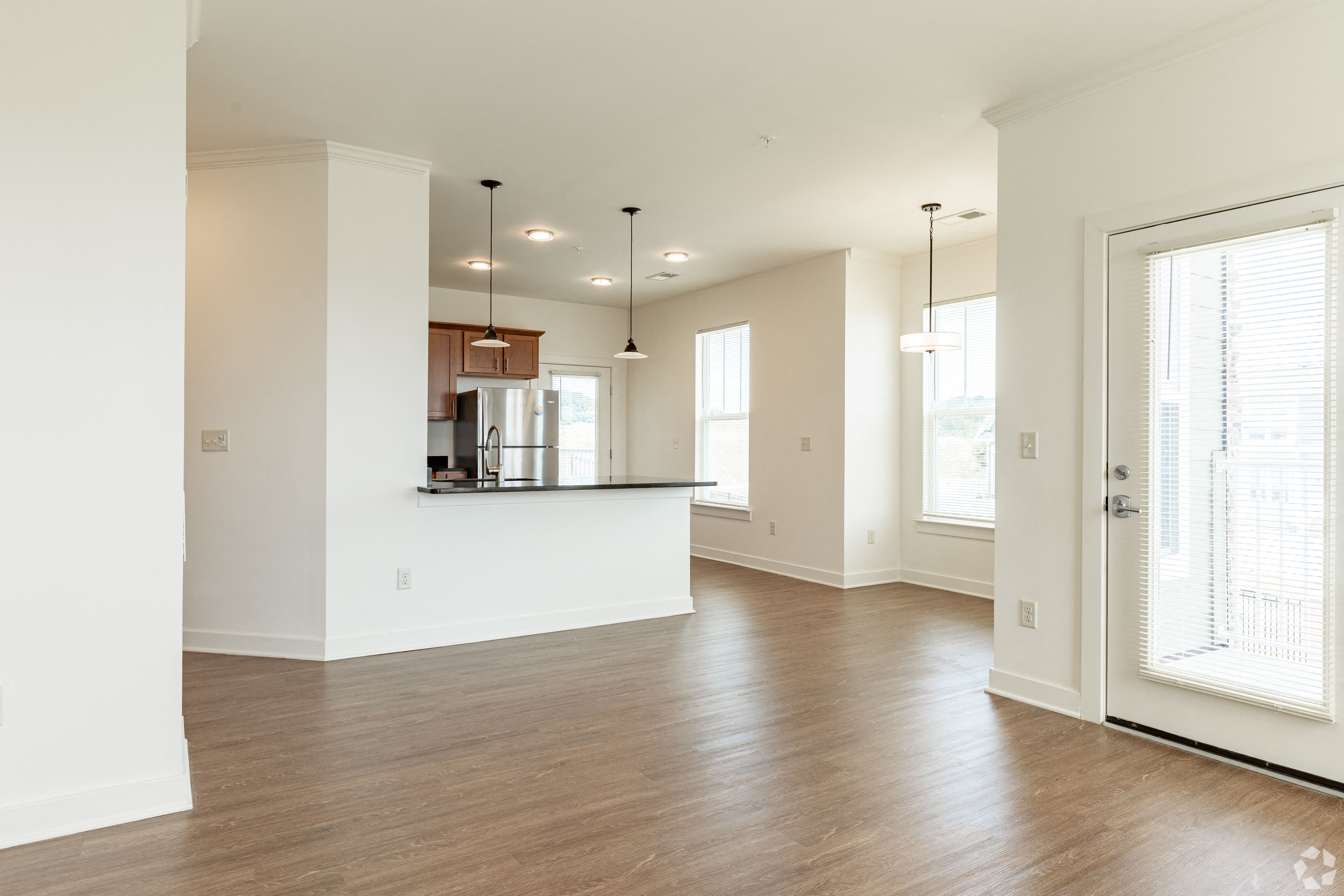 an empty kitchen and living room with a door to the kitchen and a window